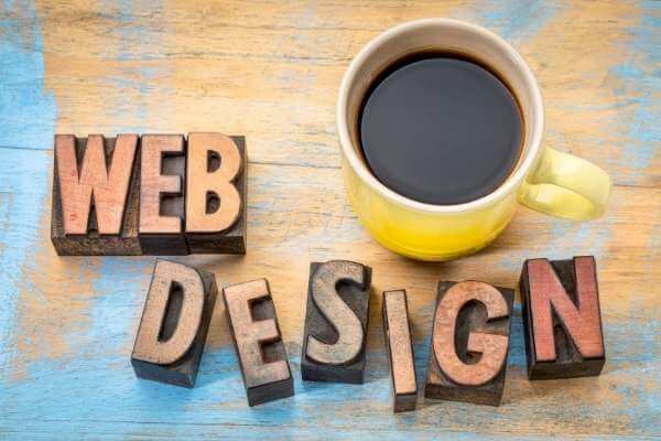 Webdesign Symbolbild - Schriftzug Webdesign und ein Becher Kaffee